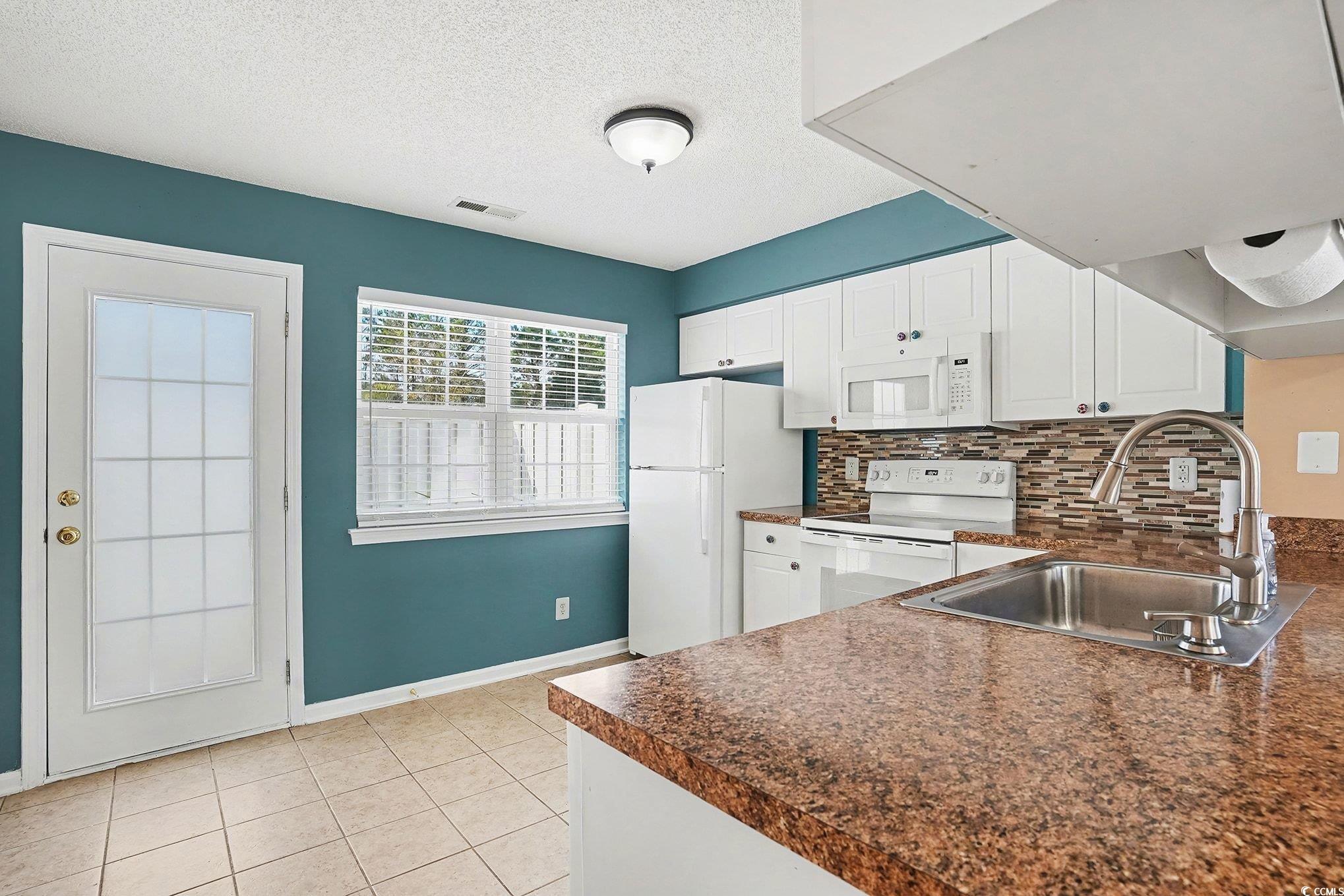 609 Sailbrooke Court, Unit 105 Murrells Inlet, SC 29576 - Photo 12 of 23 Kitchen featuring dark countertops, white cabinets, white appliances, decorative backsplash, and a textured ceiling