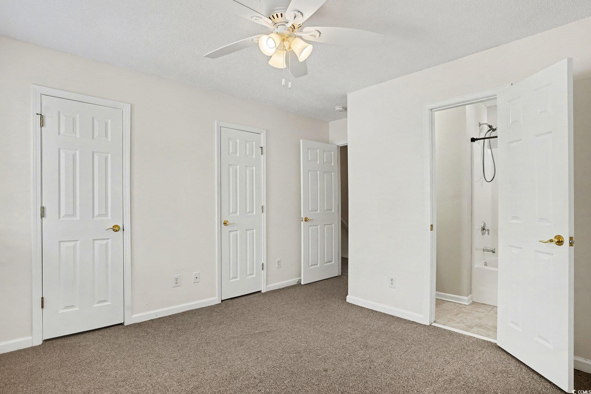 609 Sailbrooke Court, Unit 105 Murrells Inlet, SC 29576 - Photo 15 of 23 Unfurnished bedroom with carpet, ceiling fan, multiple closets, and a textured ceiling