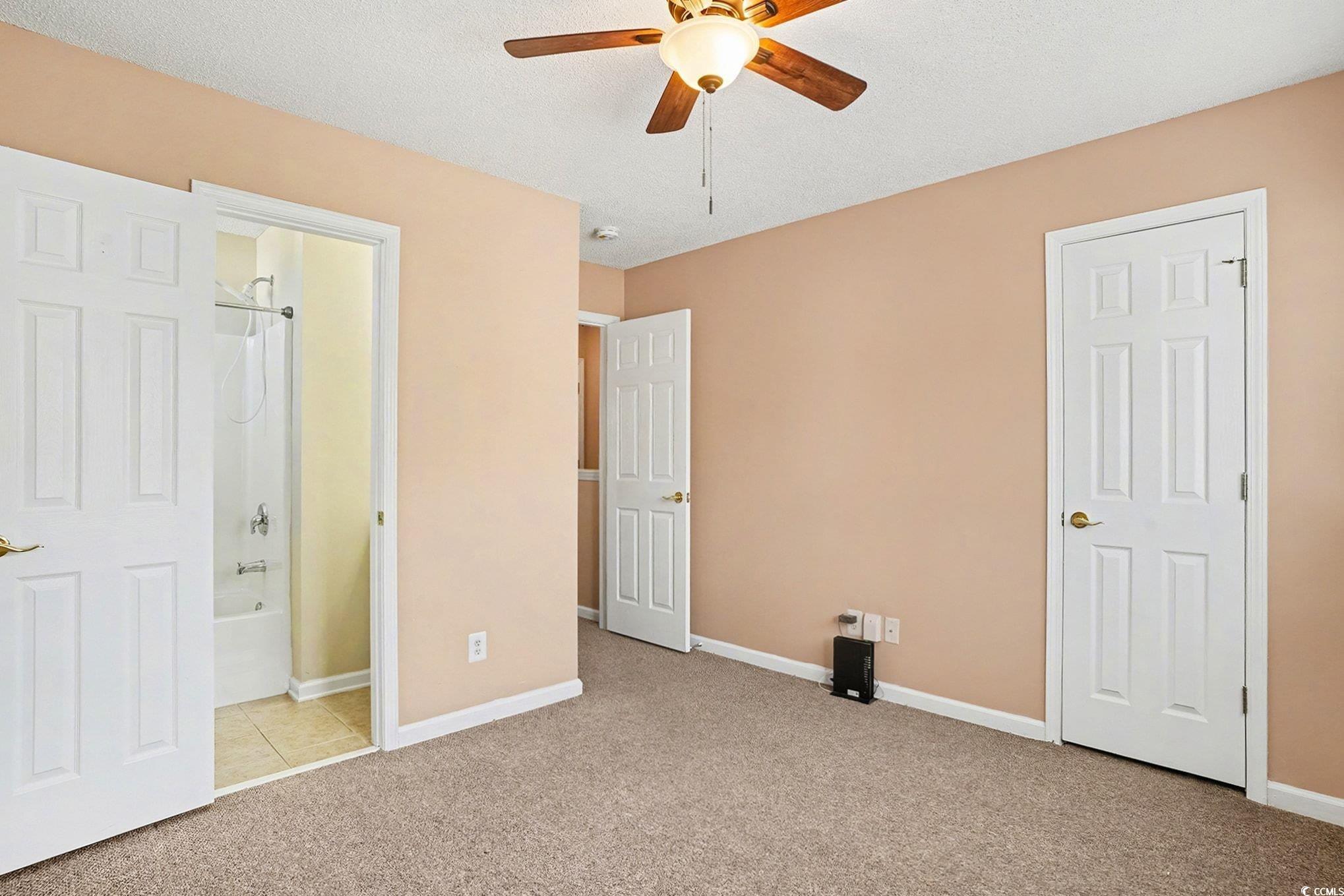 609 Sailbrooke Court, Unit 105 Murrells Inlet, SC 29576 - Photo 18 of 23 Unfurnished bedroom featuring light colored carpet, connected bathroom, ceiling fan, and a textured ceiling