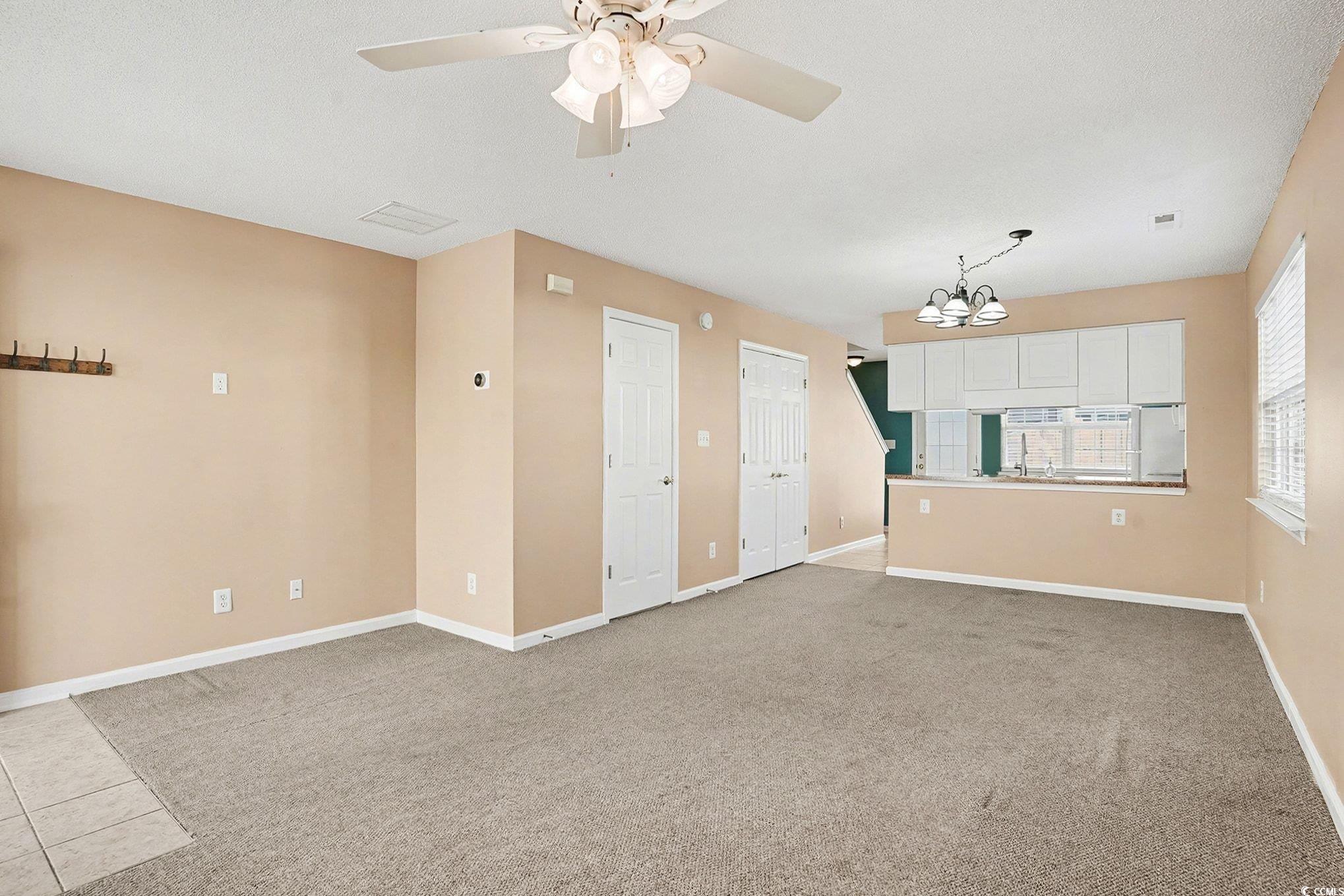 609 Sailbrooke Court, Unit 105 Murrells Inlet, SC 29576 - Photo 6 of 23 Empty room featuring light colored carpet, a chandelier, and ceiling fan