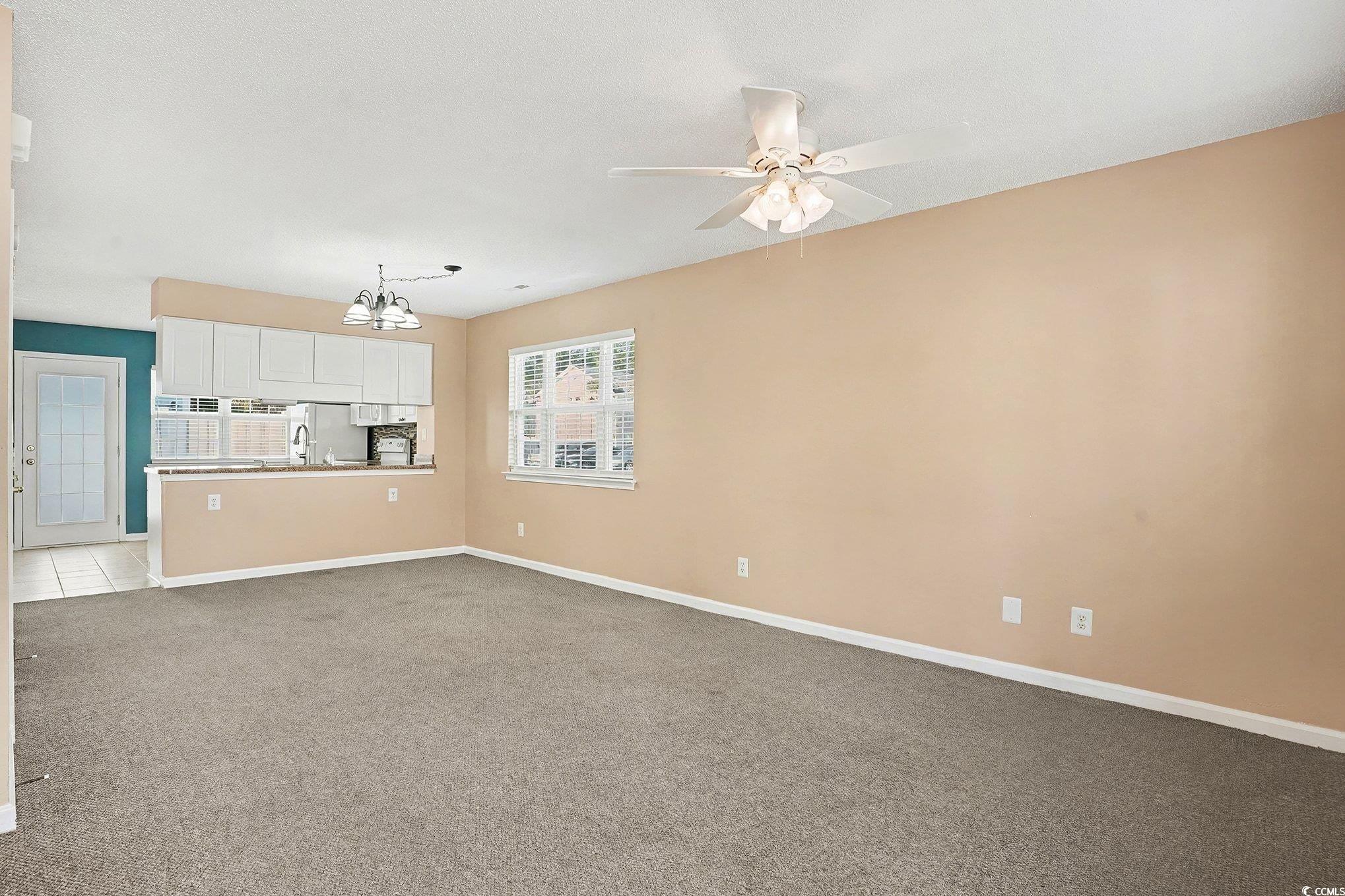 609 Sailbrooke Court, Unit 105 Murrells Inlet, SC 29576 - Photo 8 of 23 Unfurnished living room with light colored carpet, a chandelier, and ceiling fan