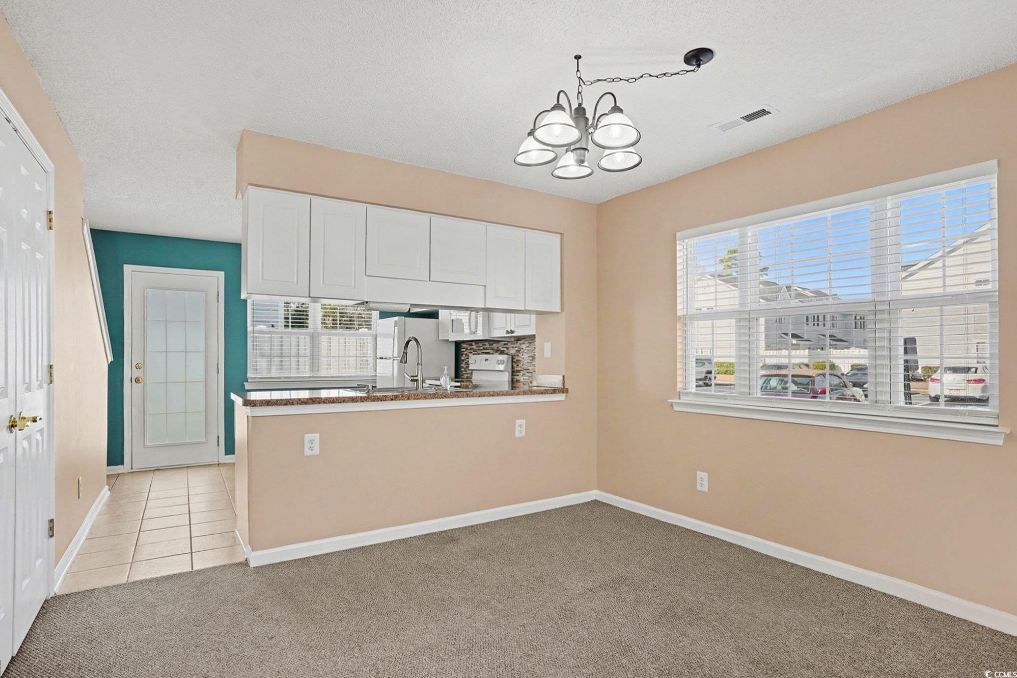 609 Sailbrooke Court, Unit 105 Murrells Inlet, SC 29576 - Photo 10 of 23 Kitchen with white cabinets, light carpet, plenty of natural light, a textured ceiling, and a chandelier