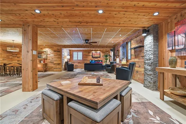 a living room with stainless steel appliances kitchen island granite countertop a table chairs and a wooden floor