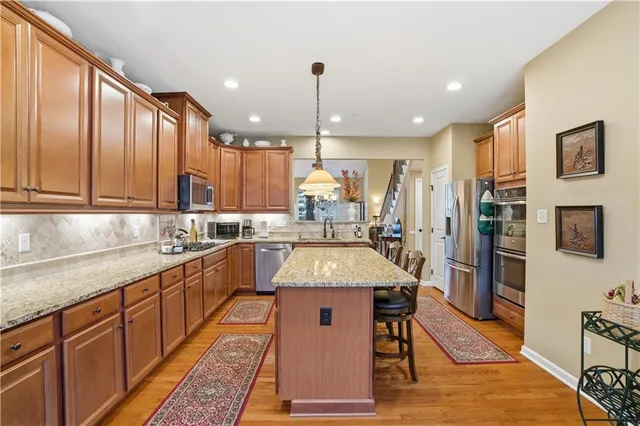 a kitchen with stainless steel appliances granite countertop wooden cabinets a sink stove and a refrigerator