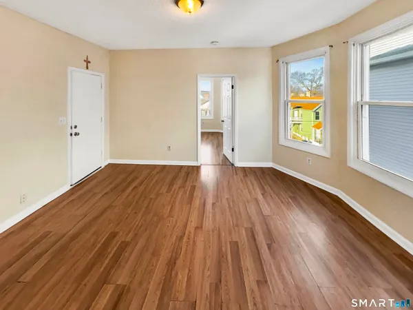 an empty room with wooden floor and windows