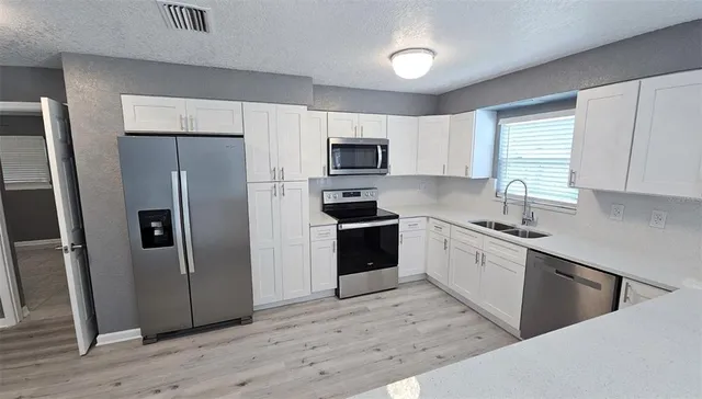 a large white kitchen with wooden floor