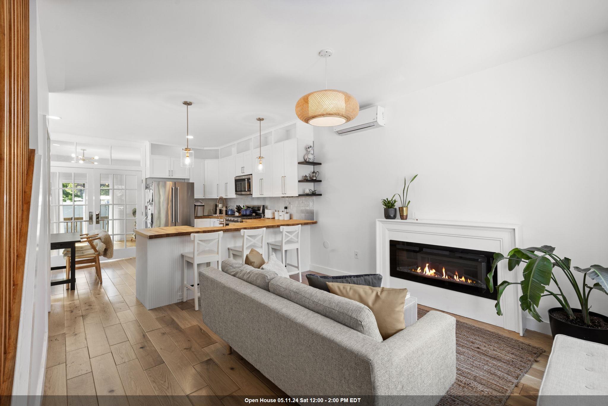 a living room with stainless steel appliances furniture a fireplace and wooden floor