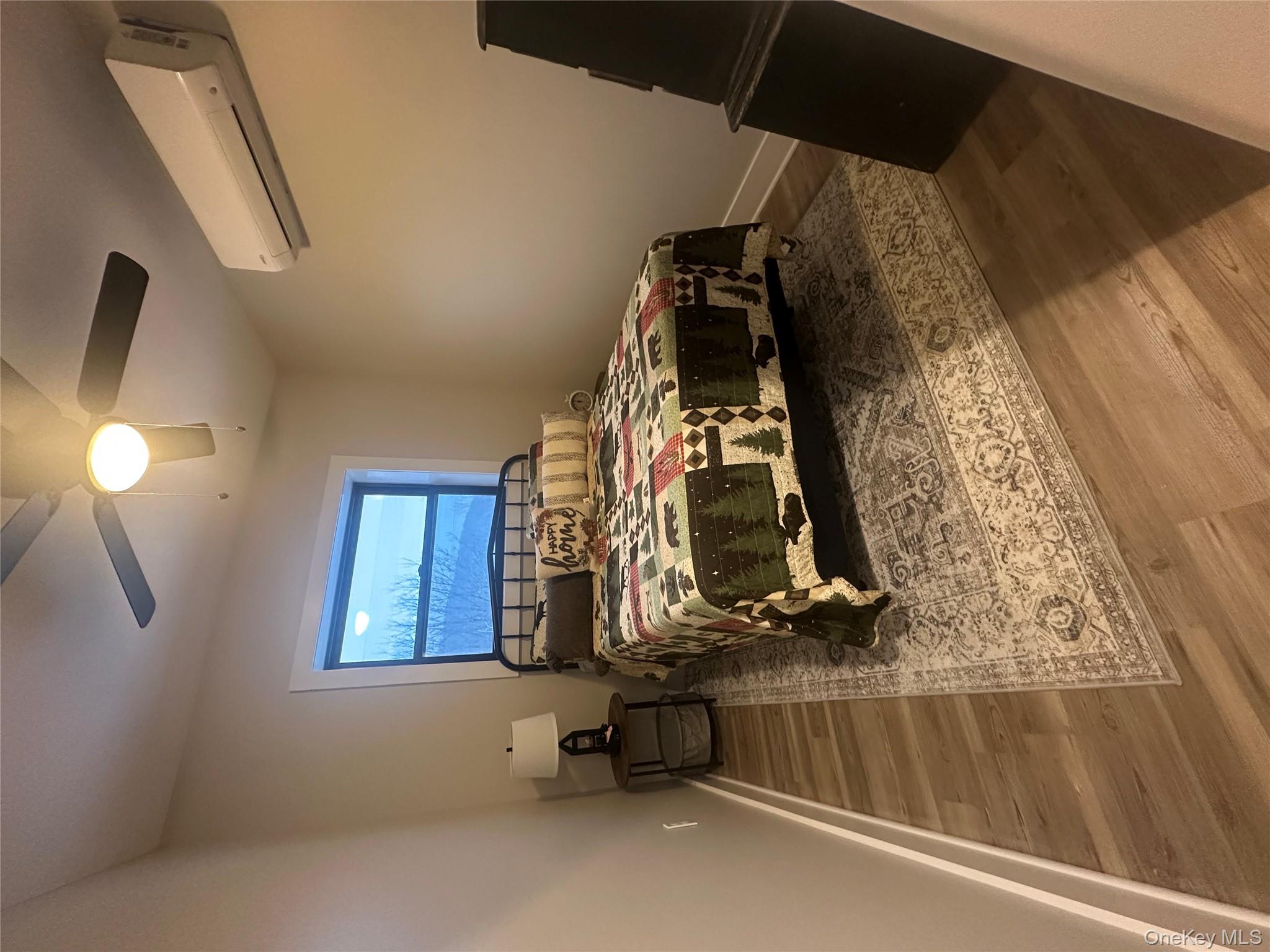 161 Hazel Road Livingston Manor, NY 12758 - Photo 22 of 24 Bedroom with wood finished floors, a wall mounted air conditioner, and a ceiling fan