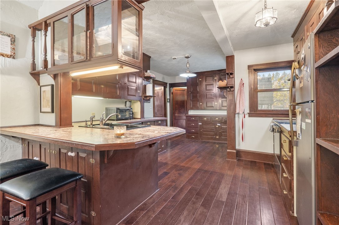 3006 Pontius Road Uniontown, OH 44685 - Photo 6 of 29 Kitchen with a kitchen breakfast bar, dark hardwood / wood-style floors, a textured ceiling, decorative light fixtures, and kitchen peninsula