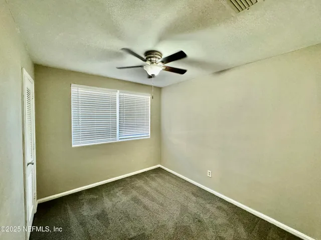 an empty room with ceiling fan and window