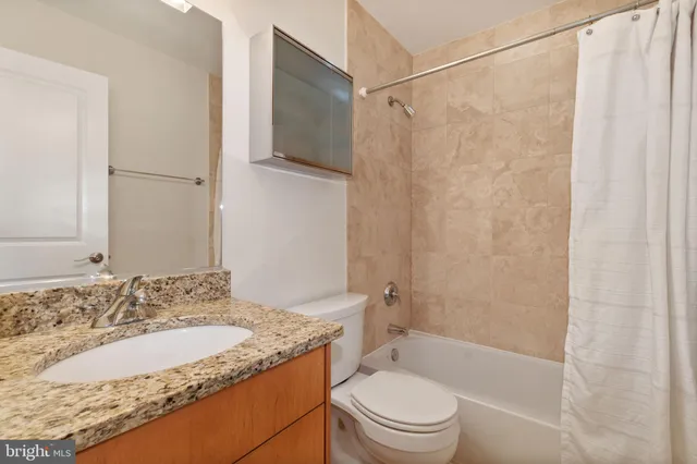 a bathroom with a granite countertop sink toilet and shower