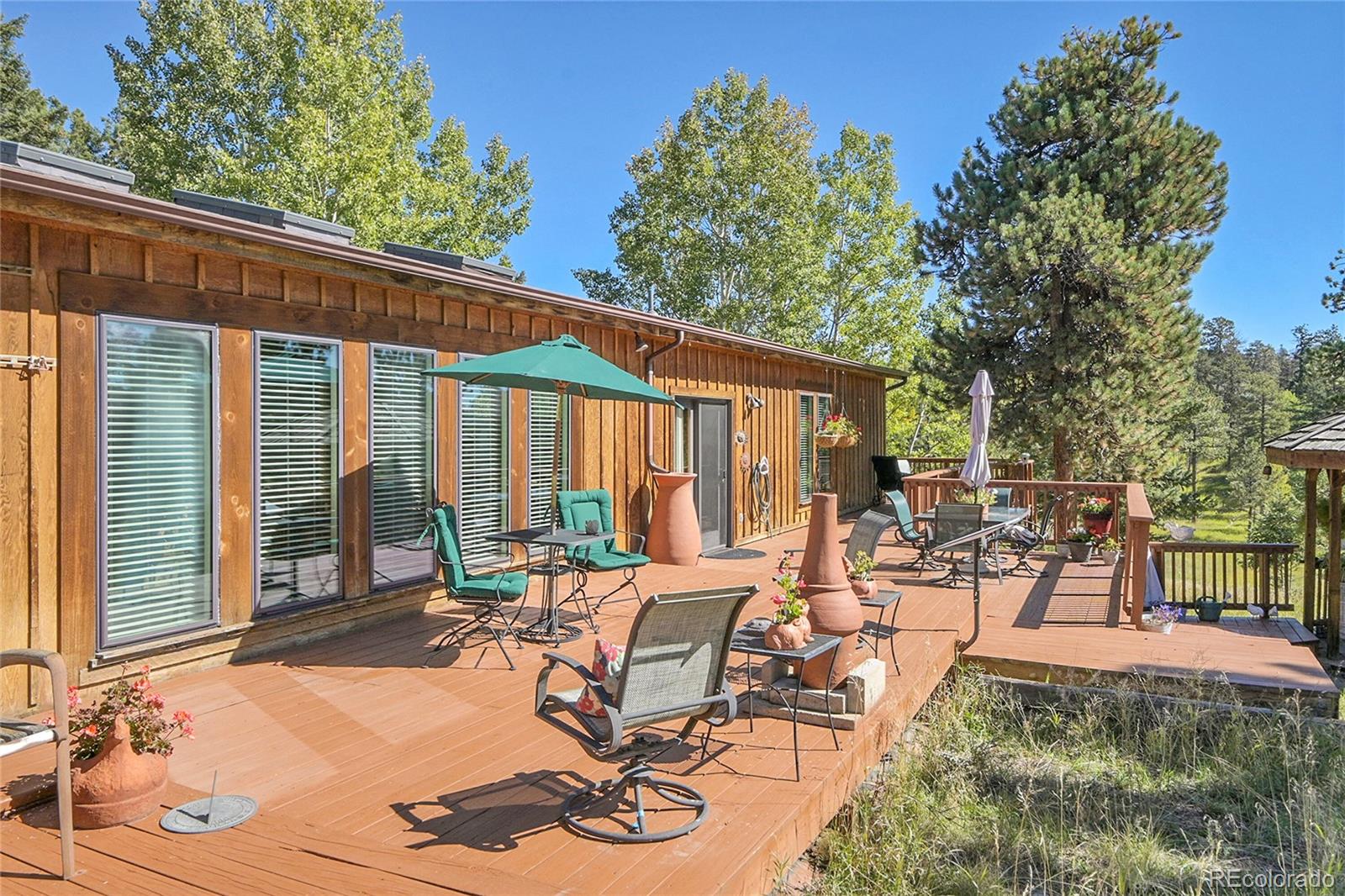 13082 South Wamblee Valley Road Conifer, CO 80433 - Photo 27 of 35 a view of a patio with table and chairs and floor to ceiling window