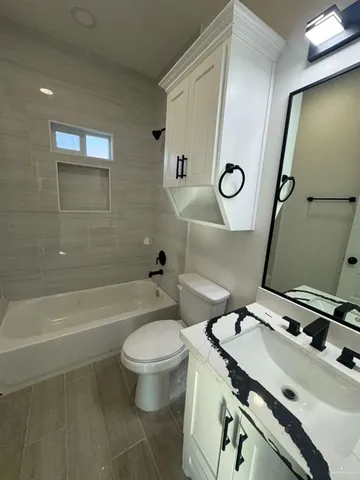 a bathroom with a granite countertop toilet a sink and a mirror