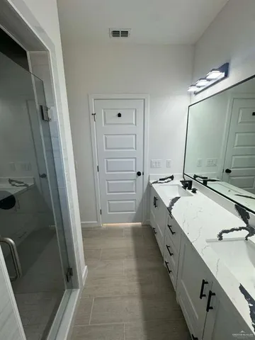 a bathroom with a double vanity sink a toilet a mirror and shower