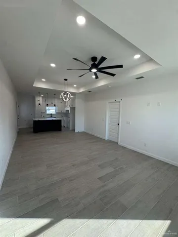 a view of empty room with wooden floor and ceiling fan