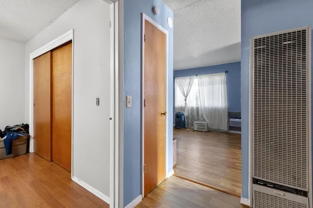 a view of a hallway with wooden floor and a bathroom