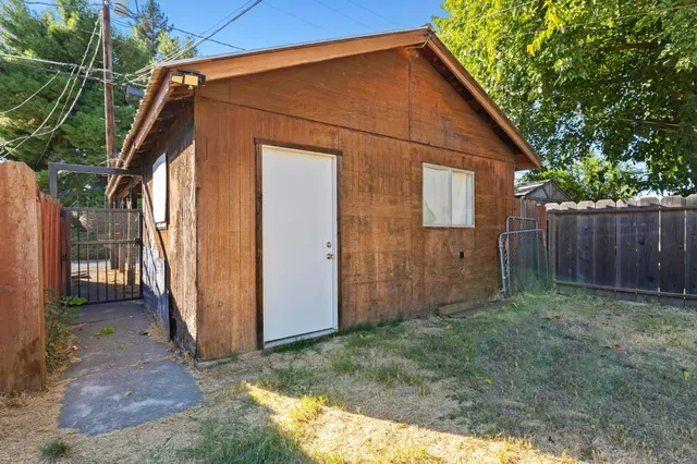 a view of backyard with small cabin and wooden fence