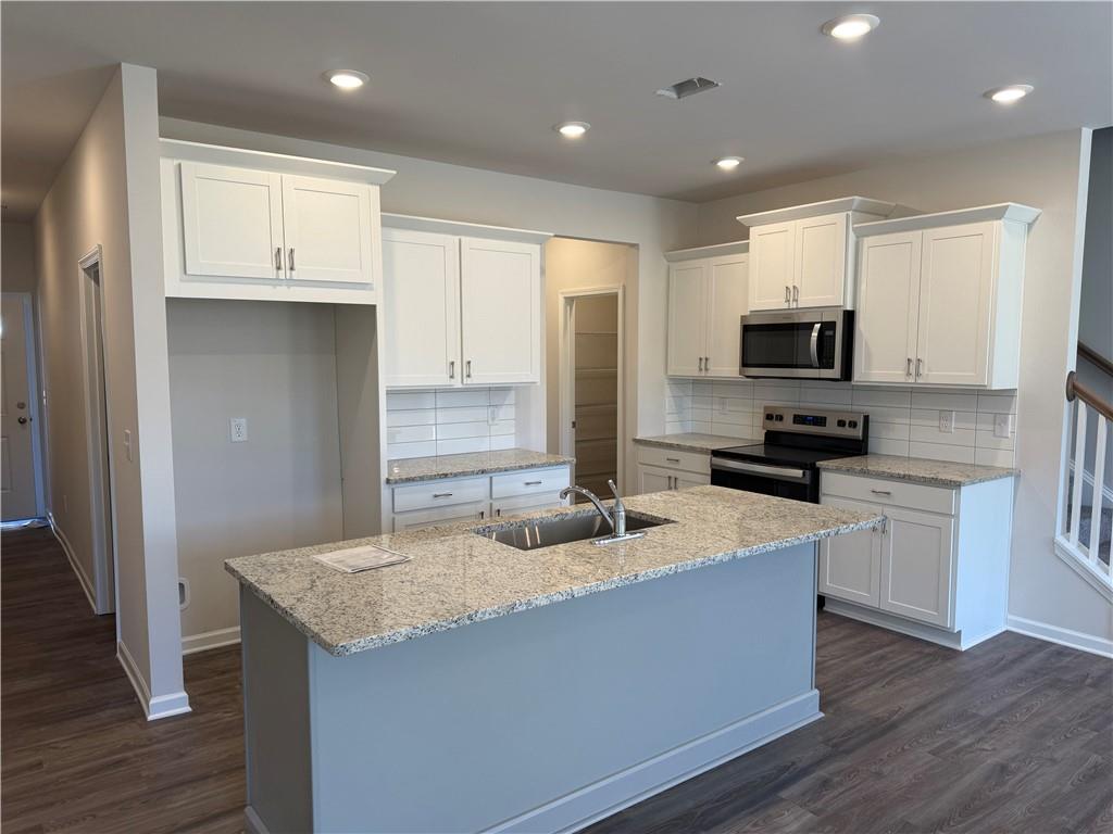 5139 Longview Run Decatur, GA 30035 - Photo 3 of 16 a kitchen with kitchen island granite countertop a stove top oven a sink a refrigerator and white cabinets with wooden floor