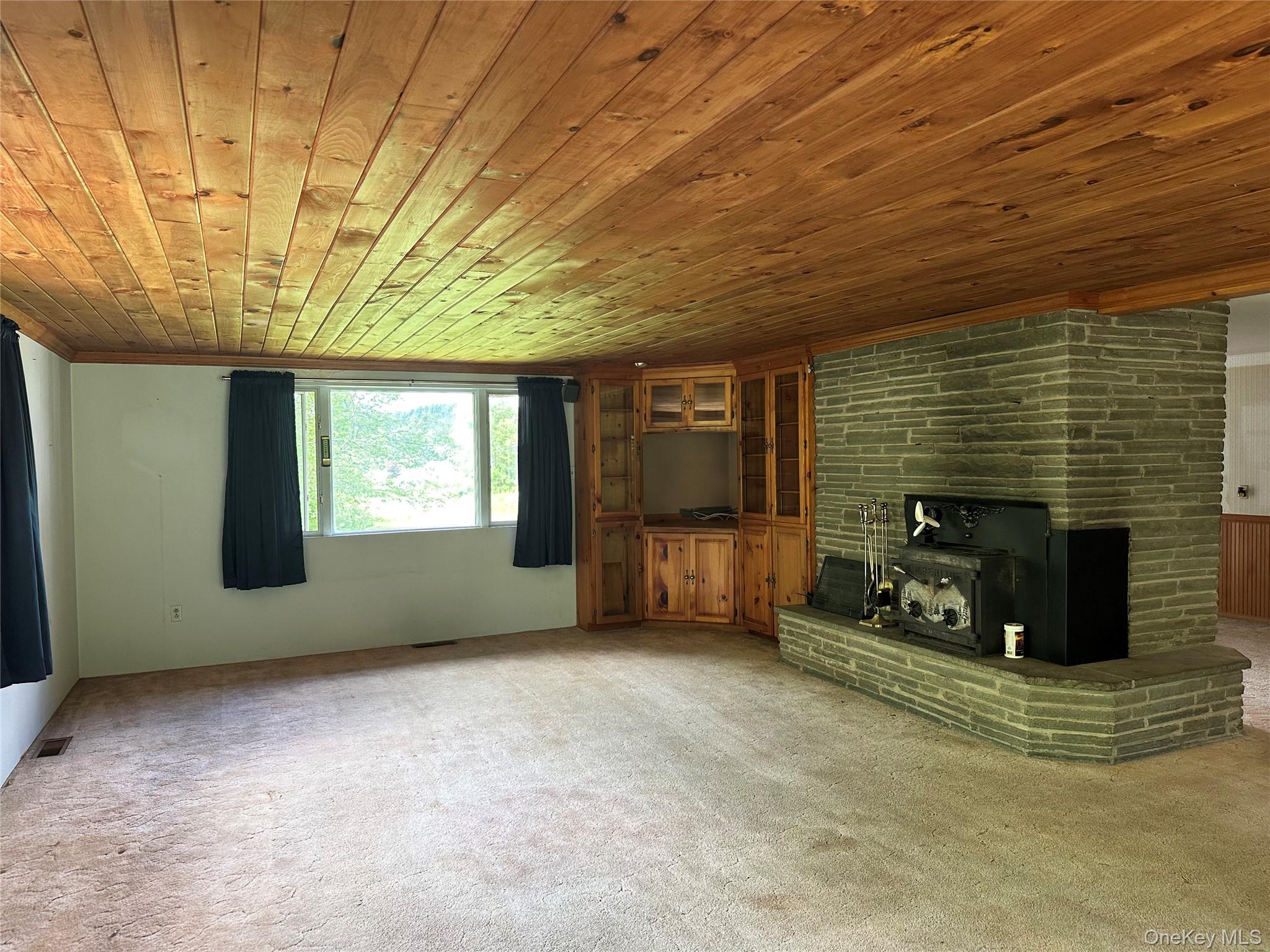818 Methol Road Roscoe, NY 12776 - Photo 20 of 39 Spacious living room with original 1960s character, wood-paneled ceiling, built-in cabinetry, and fireplace designed for both heating and cooking.