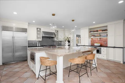 a kitchen with stainless steel appliances granite countertop a table chairs and a refrigerator