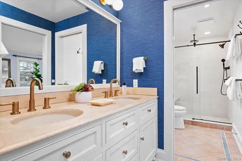 a bathroom with a double vanity sink toilet and shower