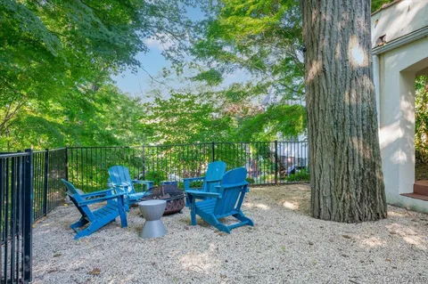 a view of a patio with table and chairs potted plants and large tree