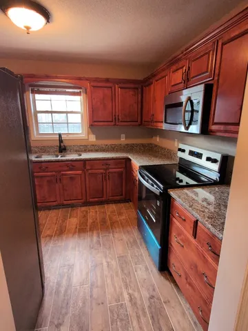 a kitchen with granite countertop a refrigerator and a stove top oven