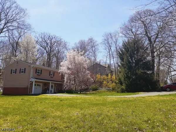 a brick house with a big yard and large trees