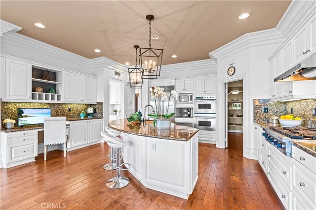 a kitchen with stainless steel appliances a dining table chairs stove and white cabinets