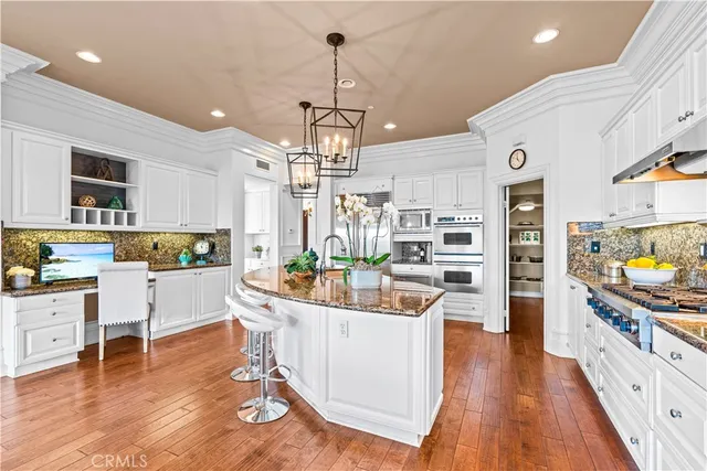 a kitchen with stainless steel appliances a dining table chairs stove and white cabinets