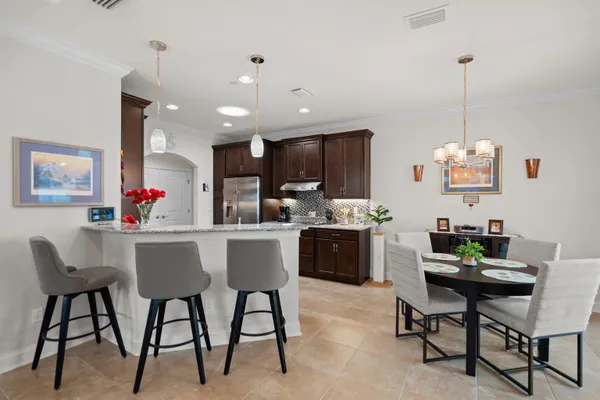 a kitchen with stainless steel appliances kitchen island granite countertop a dining table chairs refrigerator and sink