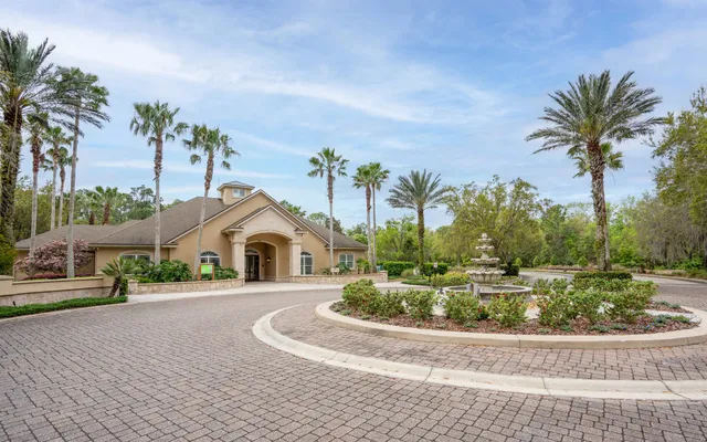 a front view of a house with a yard and palm trees