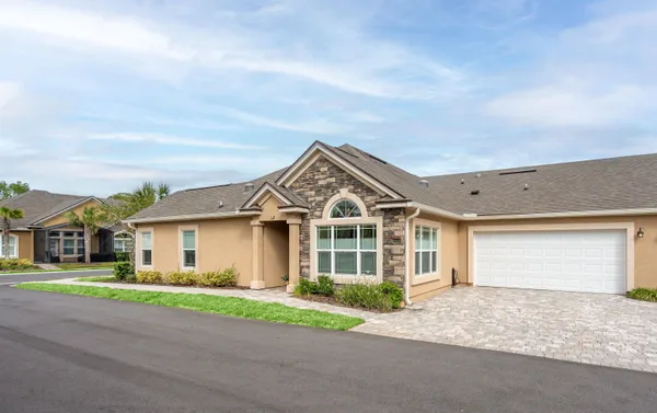 a front view of a house with a garden and trees