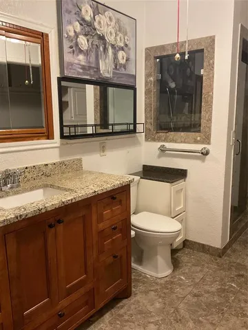 a bathroom with a granite countertop toilet sink and mirror