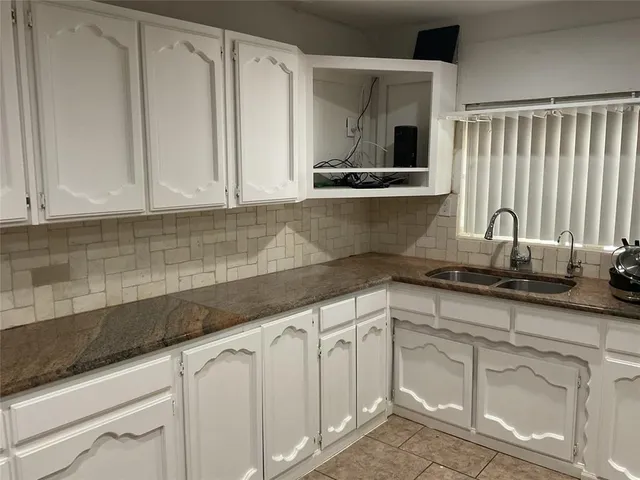 a kitchen with granite countertop white cabinets and sink