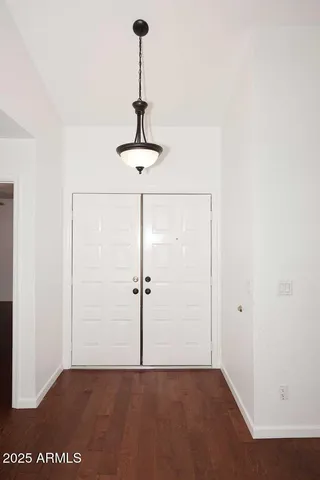 a view of a room with a chandelier fan and wooden floor