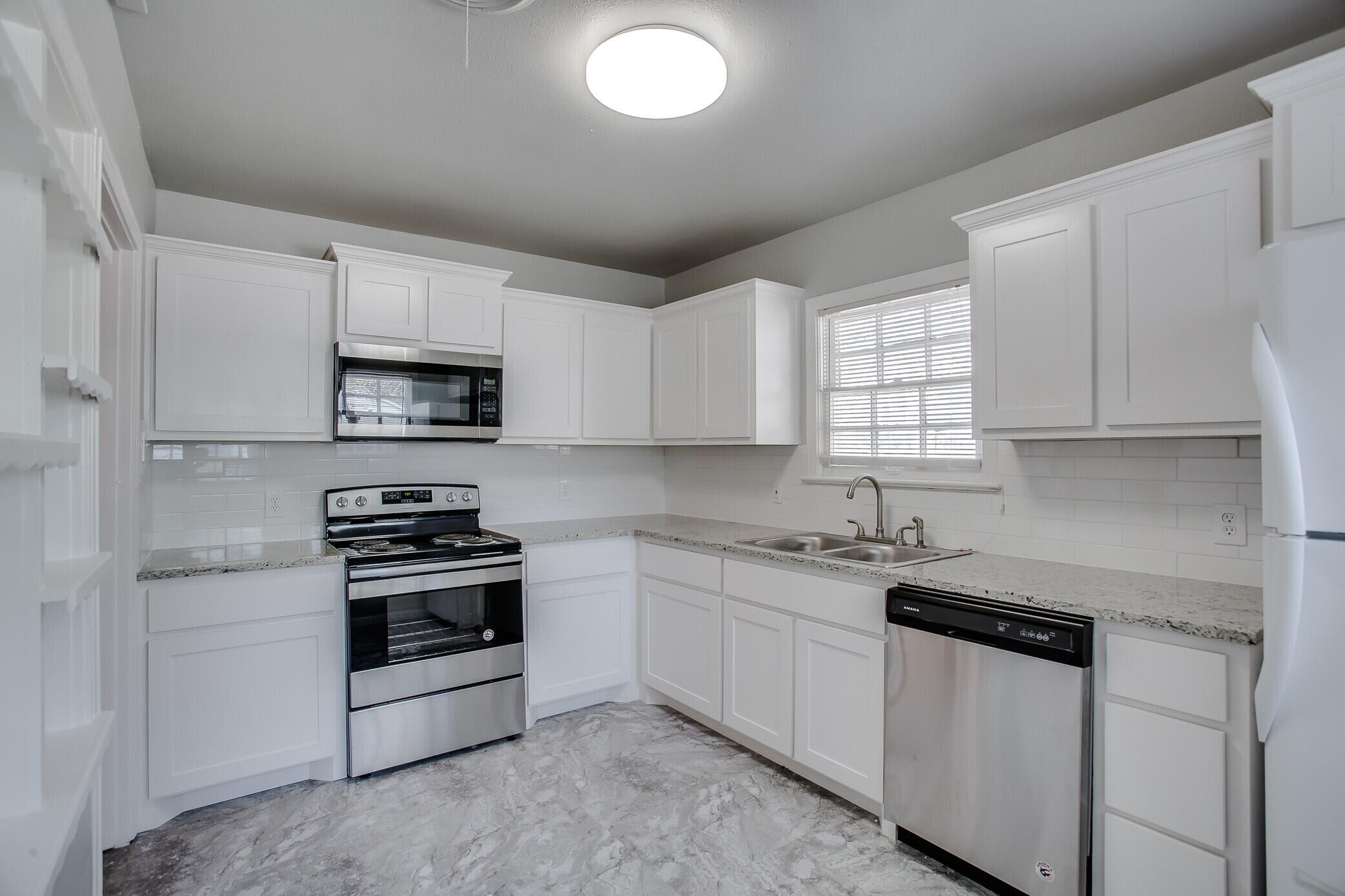 2412 22nd Street Lubbock, TX 79411 - Photo 7 of 18 a kitchen with white cabinets stainless steel appliances and sink