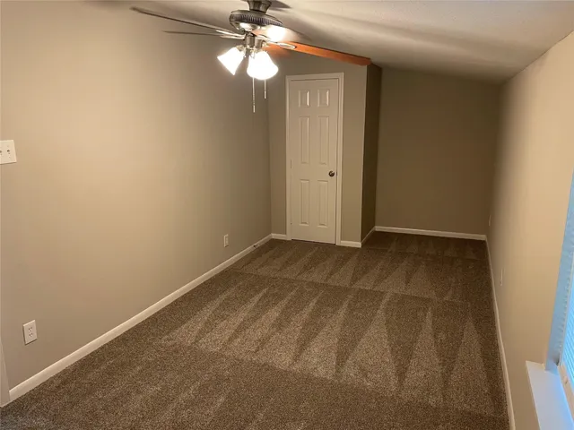 an empty room with a chandelier fan and a bathroom
