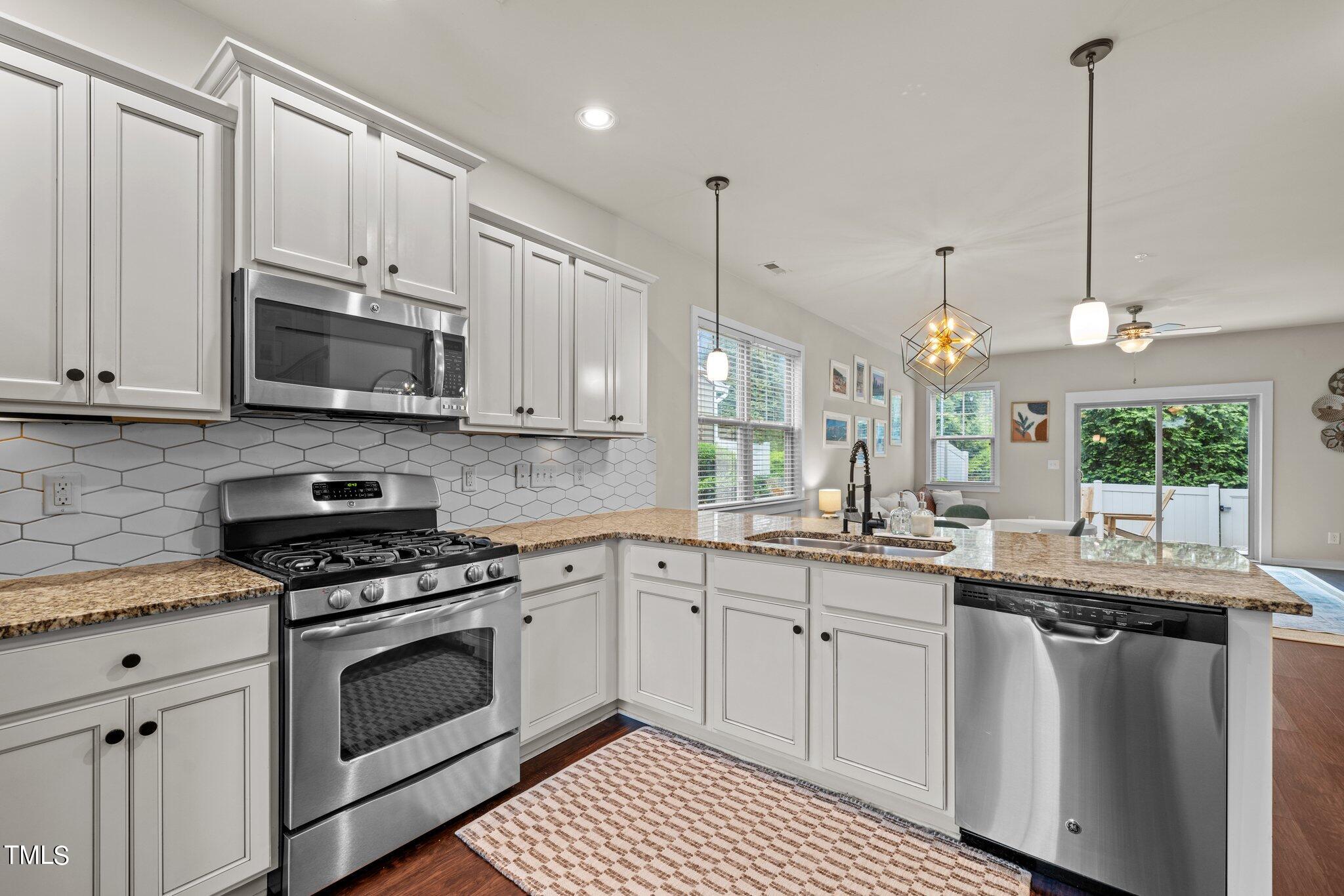 7837 Allscott Way Raleigh, NC 27612 - Photo 4 of 17 a kitchen with granite countertop a sink a window and stainless steel appliances