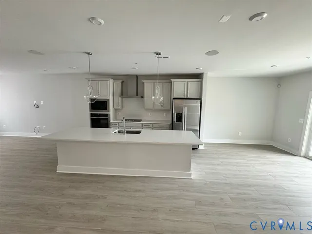 a view of an empty room and kitchen with electric equipment