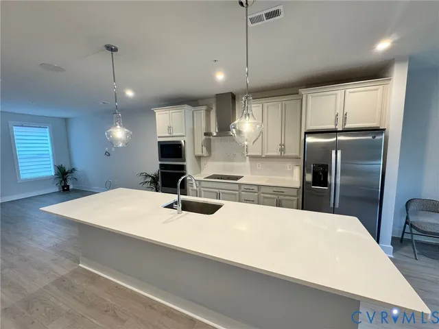 a large kitchen with kitchen island a counter space a sink appliances and cabinets