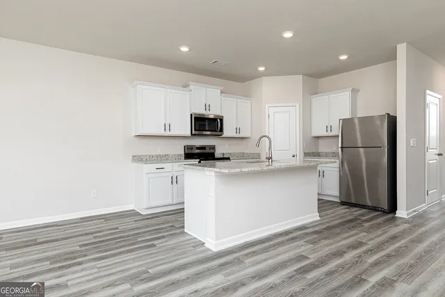 a kitchen with a refrigerator cabinets and wooden floor