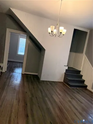 a view of an empty room with wooden floor and stairs