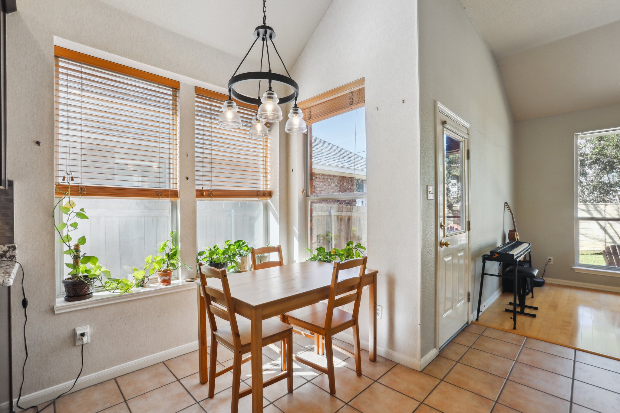 13541 Anarosa Loop Austin, TX 78727 - Photo 7 of 27 Dining area featuring abundant natural light from multiple windows, vaulted ceilings, a contemporary chandelier, and tile flooring
