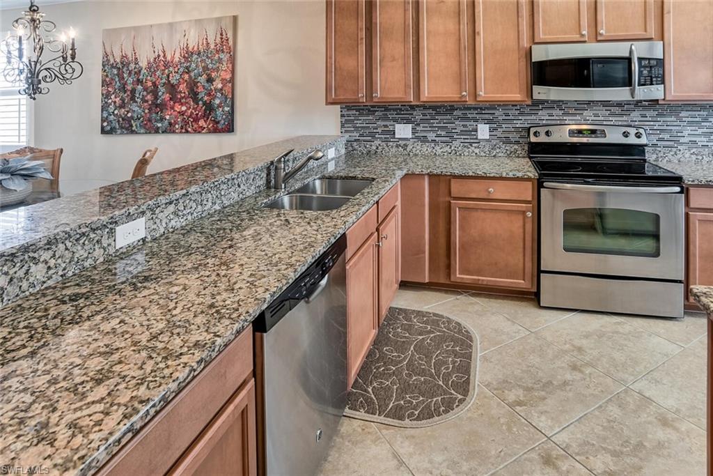 9719 Acqua Court, Unit 228 Naples, FL 34113 - Photo 7 of 35 a kitchen with stainless steel appliances granite countertop a stove sink and cabinets