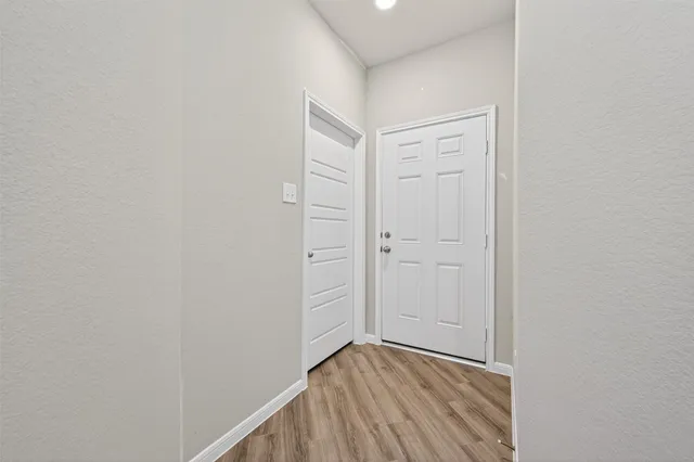a view of a hallway with wooden floor and entryway