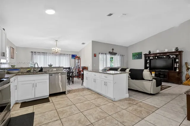 a kitchen with stainless steel appliances granite countertop a refrigerator sink and white cabinets