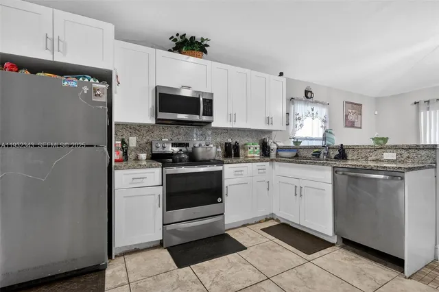a kitchen with a refrigerator sink and white cabinets