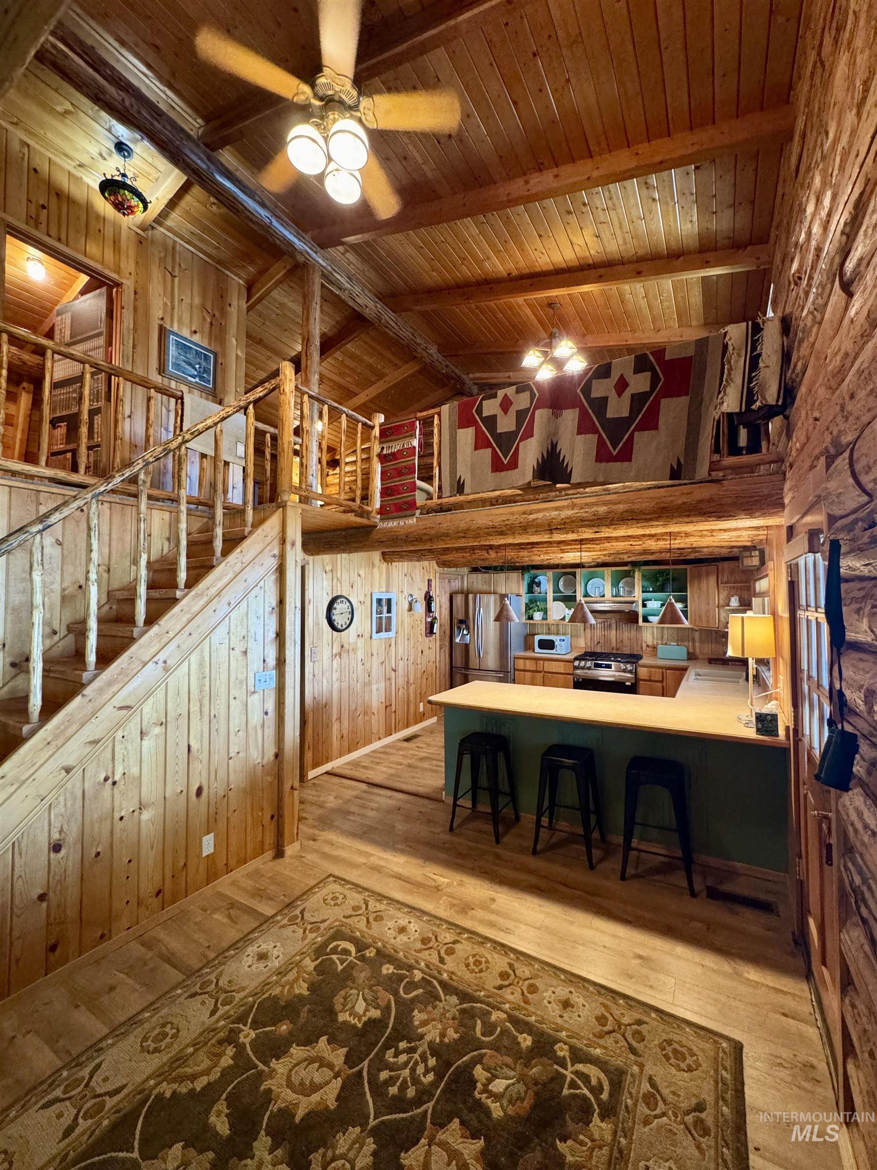 62 Bell Rapids Road Hagerman, ID 83332 - Photo 8 of 34 Expansive open-concept interior featuring wood-panel walls, wood-finish flooring, and exposed wood beams