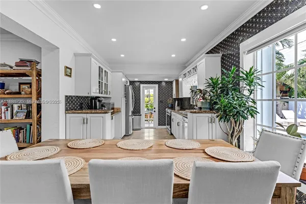 a kitchen that has a sink a stove and a dining table with chairs